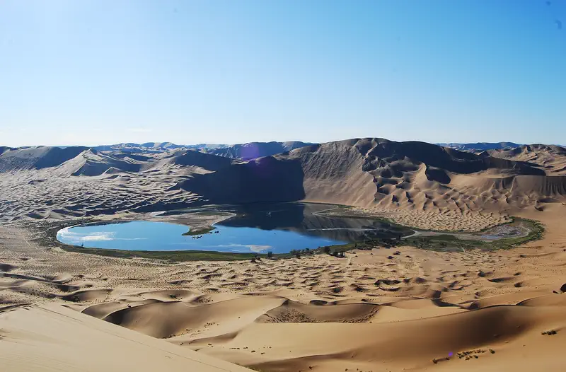 Badain Jaran Desert: a blue lake ringed by tall sand dunes