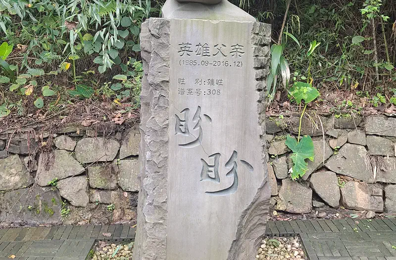 Dujiangyan Panda Base: stone panda sculpture on a rock marker among greenery