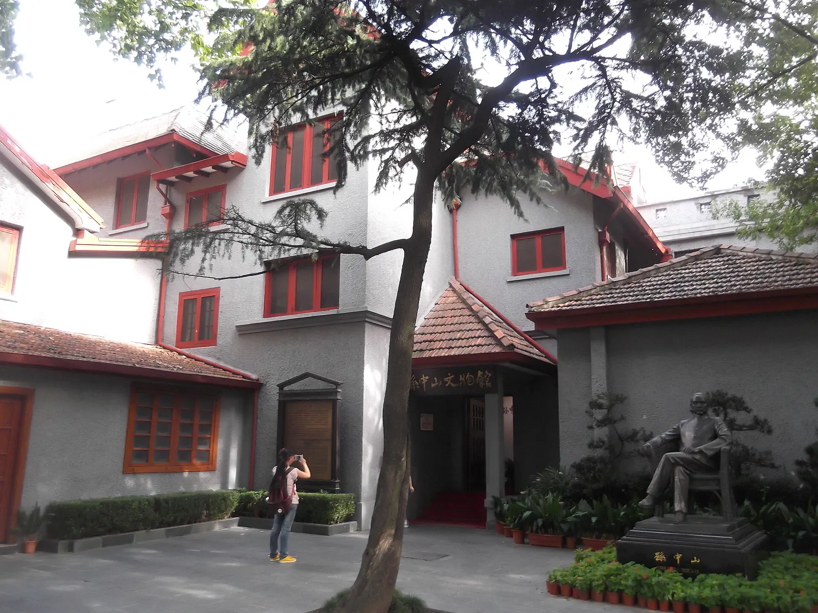Former Residence of Sun Yat-sen: a two-storey grey villa with red window frames and a seated statue in the garden