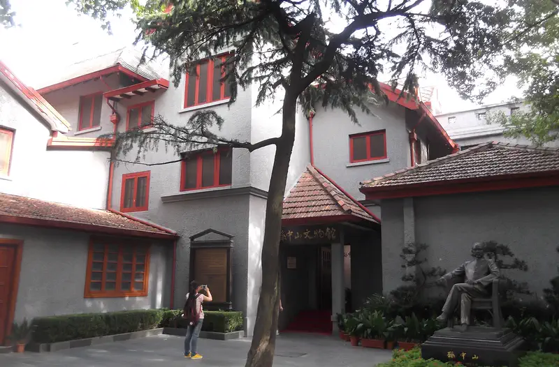 Former Residence of Sun Yat-sen: a two-storey grey villa with red window frames and a seated statue in the garden