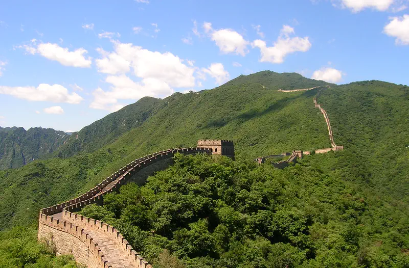 Great Wall: wall winding along a green mountain ridge under blue sky