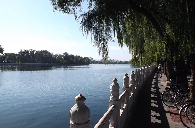 Houhai Lakes: lake with willow trees along a railed path, bicycles parked nearby