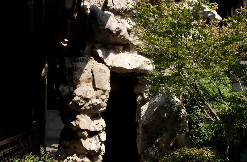 Hu Xueyan's Mansion: garden with rockery stones and greenery beside a building