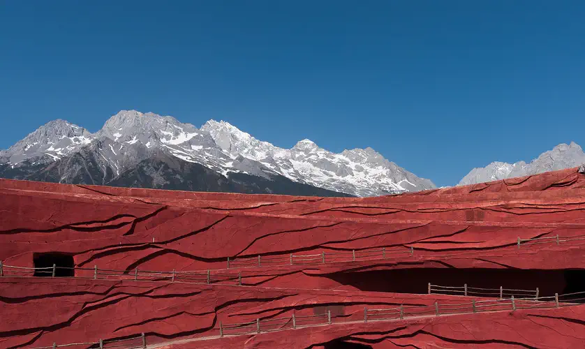 Jade Dragon Snow Mountain: snow-covered peaks rising beyond the red terraces of an open-air theatre stage