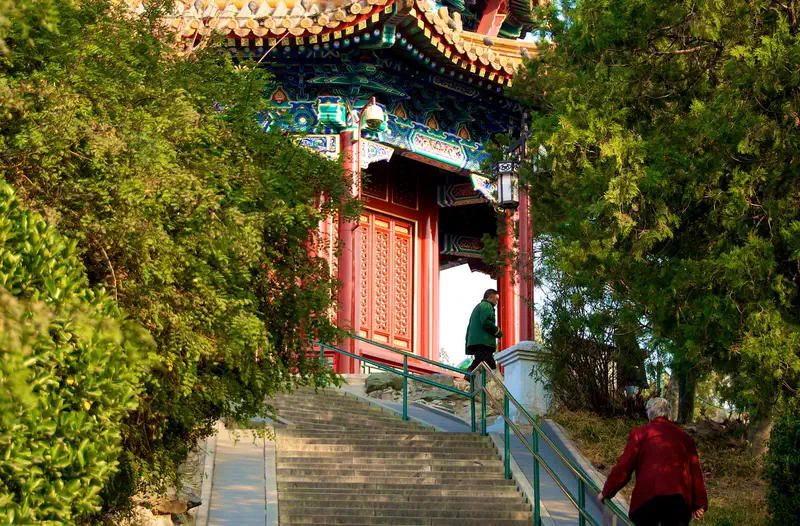 Jingshan Park: pavilion with a blue-green tiled roof atop a hill, framed by trees beside a stairway