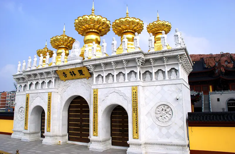 Donglin Temple (East Forest Monastery): white gate with gold-topped spires and arched doorways beside a tiled temple roof