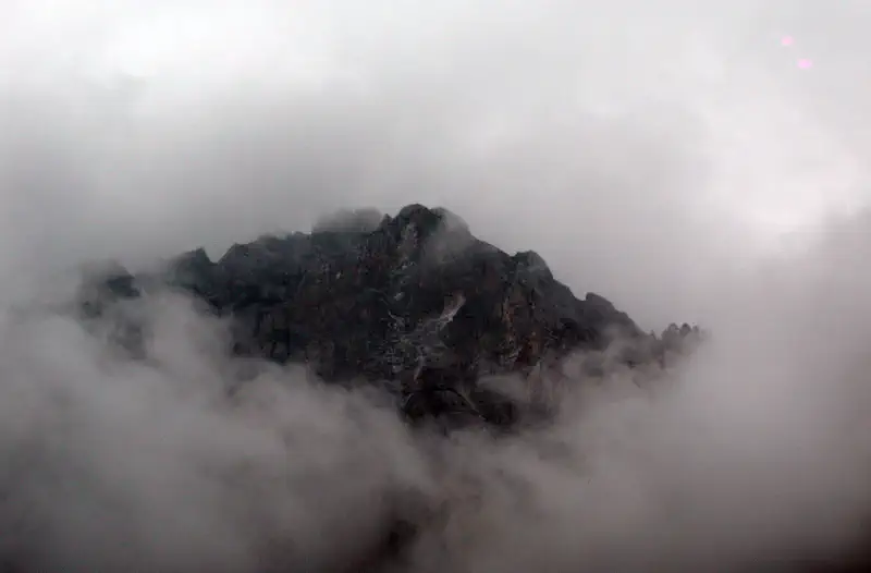 Jiuzhaigou Valley: dark mountain peak partially hidden by thick white cloud and mist