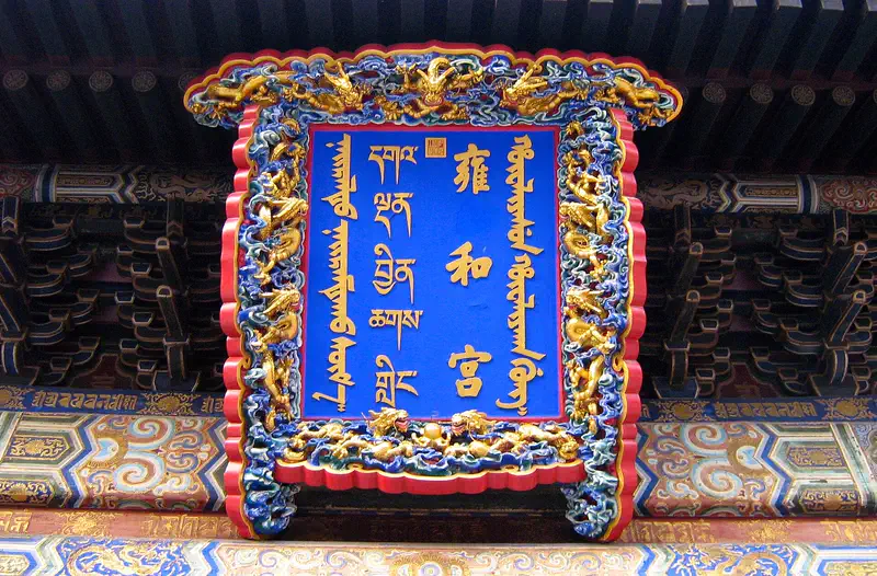 Lama Temple (Yonghe Gong): blue temple plaque with gold script framed by an ornate red and gold carved border