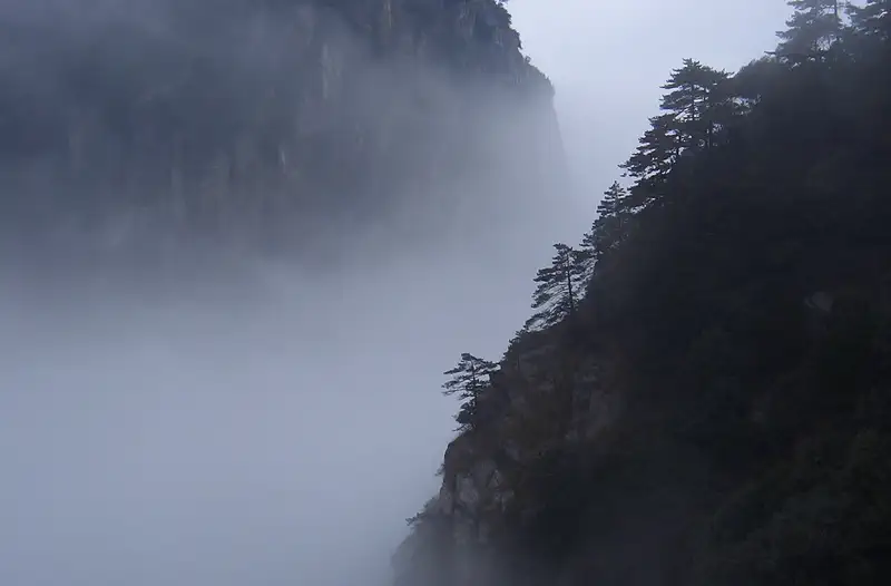 Mt Lu (Lushan): dark mountain peak partially shrouded in thick white mist against a grey sky