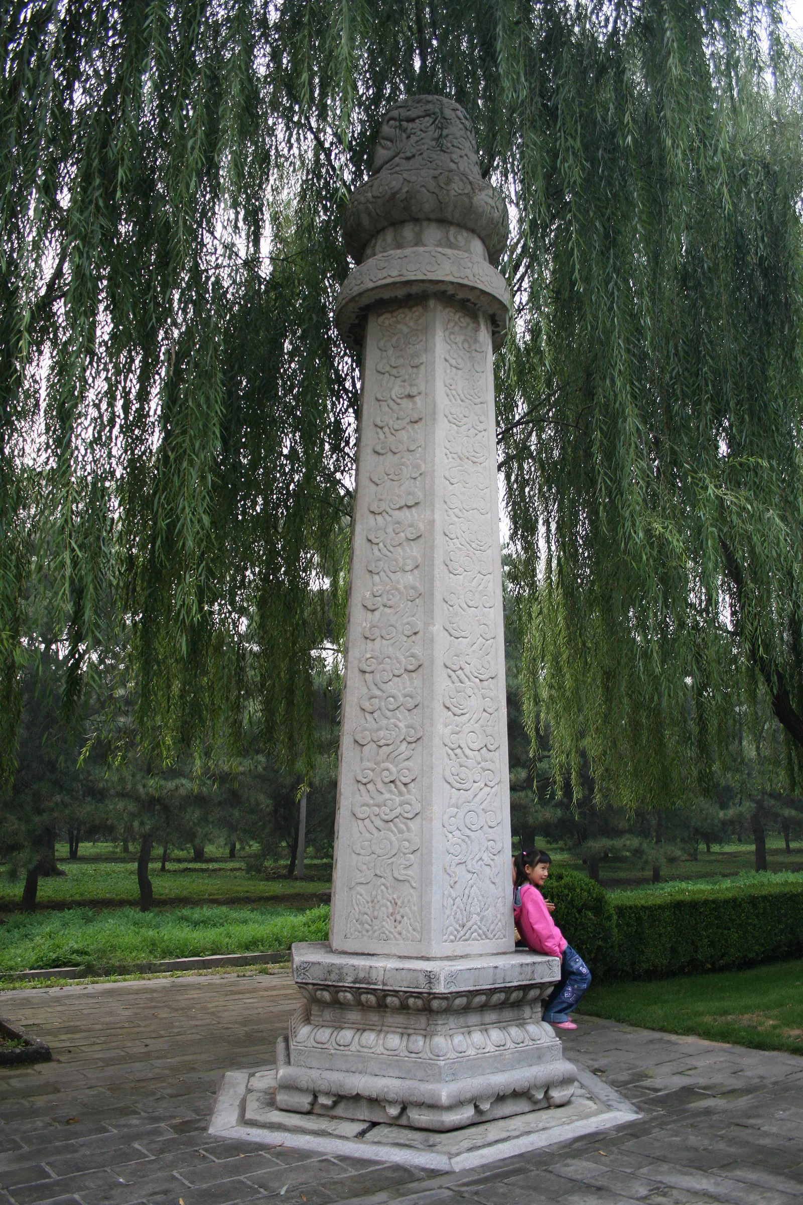 Ming Tombs and Sacred Way: tall carved white stone pillar standing in a grassy park among trees