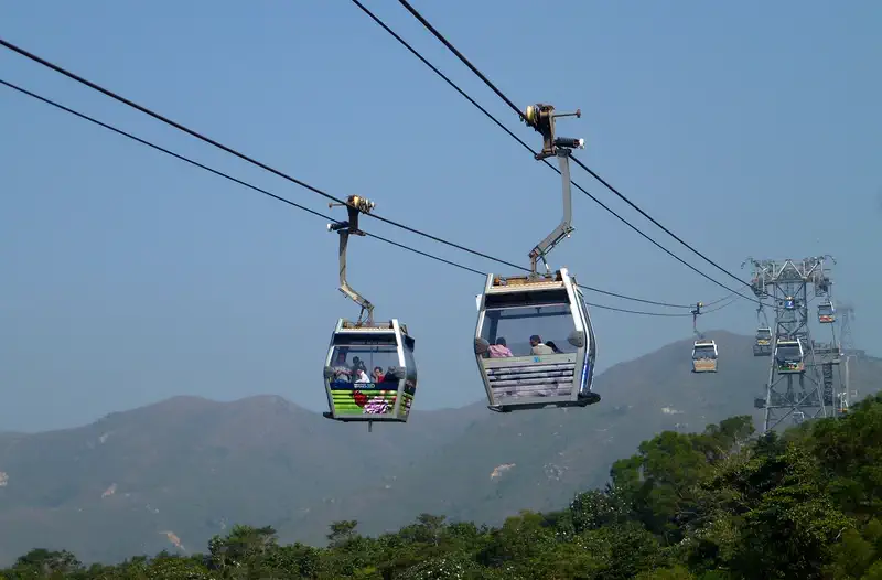 Ngong Ping 360: cable-car cabins crossing above forested hills