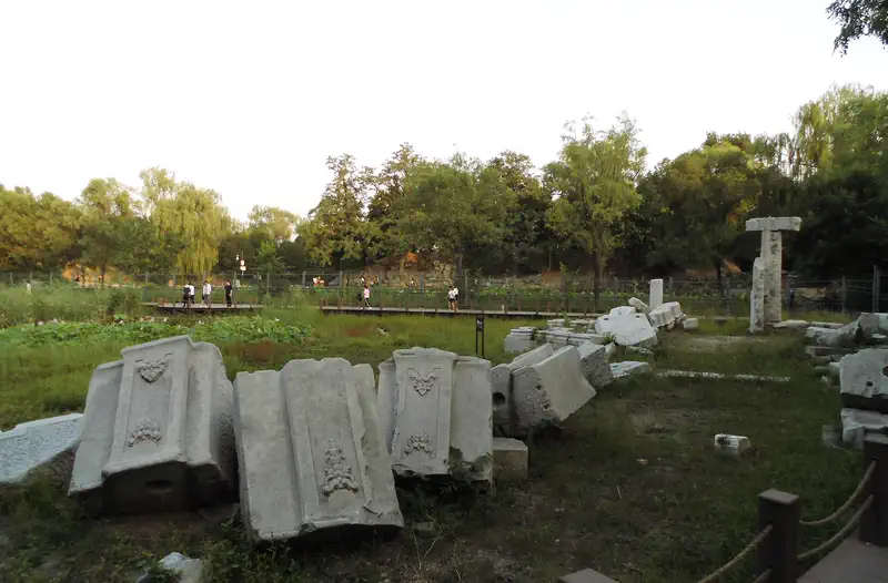 Old Summer Palace (Yuanmingyuan): scattered white marble stone ruins lying on a grassy field