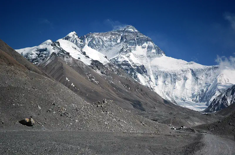 Rongbuk Monastery: massive snow-capped peak rising above a rocky valley floor under a clear blue sky