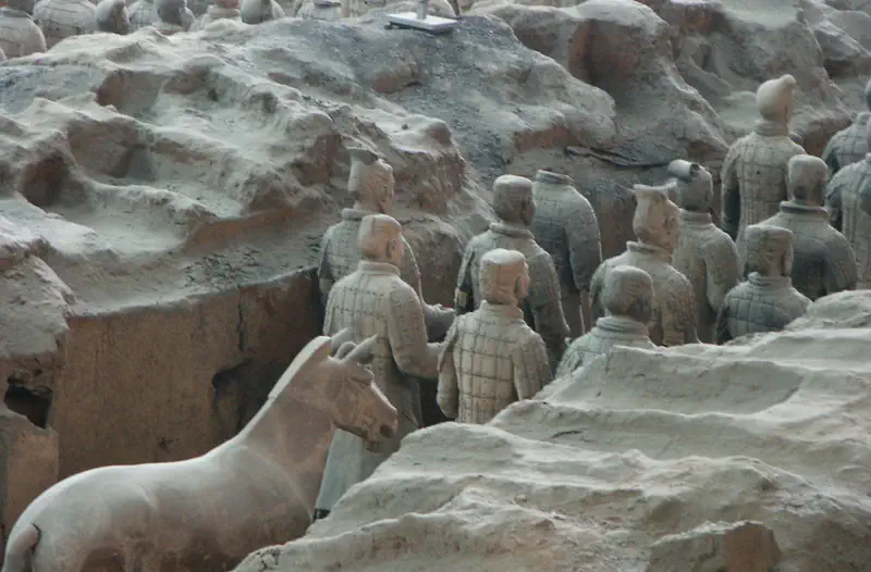 Terracotta Army: rows of grey terracotta warrior figures partially excavated in an earthen pit