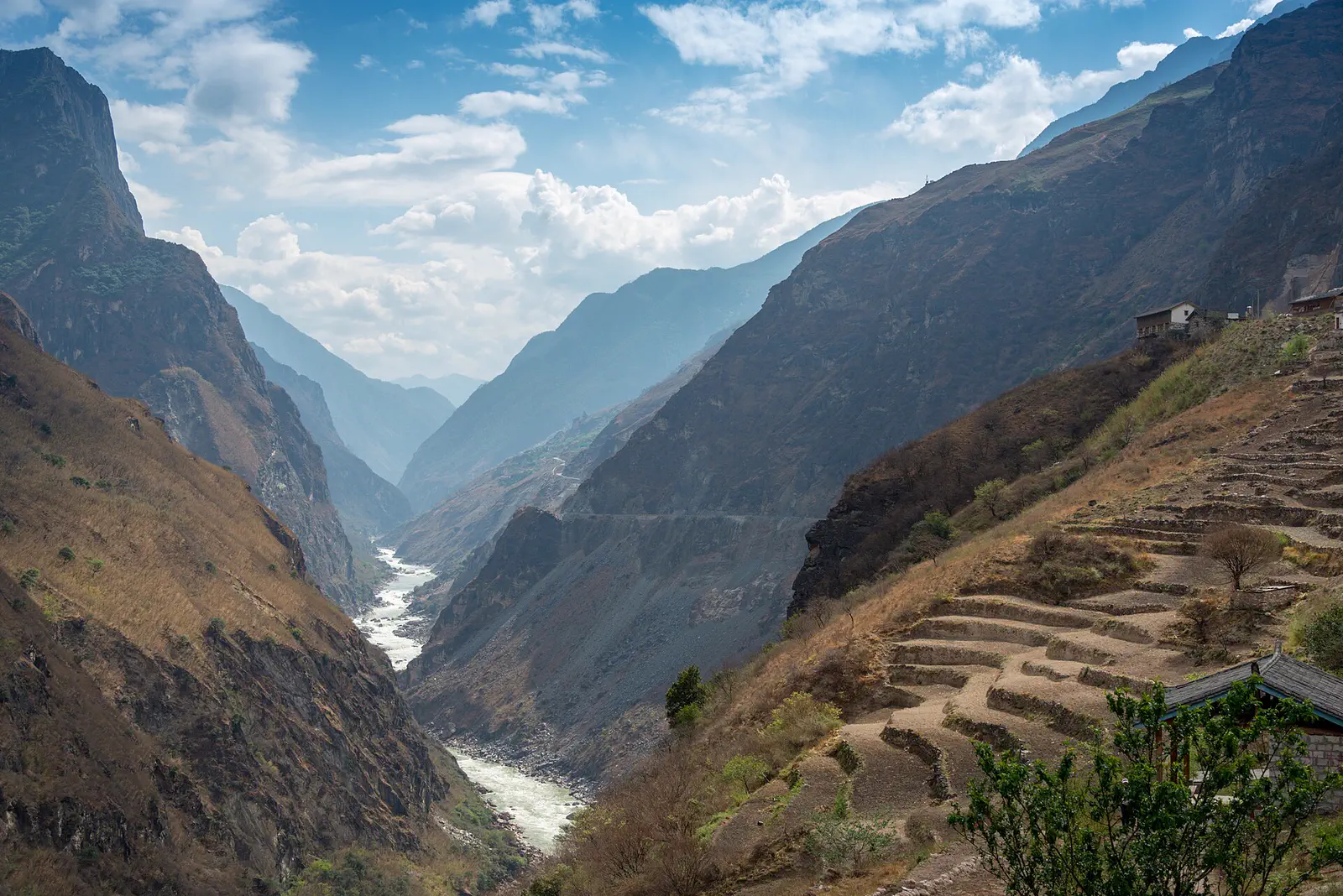Three Parallel Rivers: a river cutting through a deep gorge with terraced slopes and hazy ridges beyond