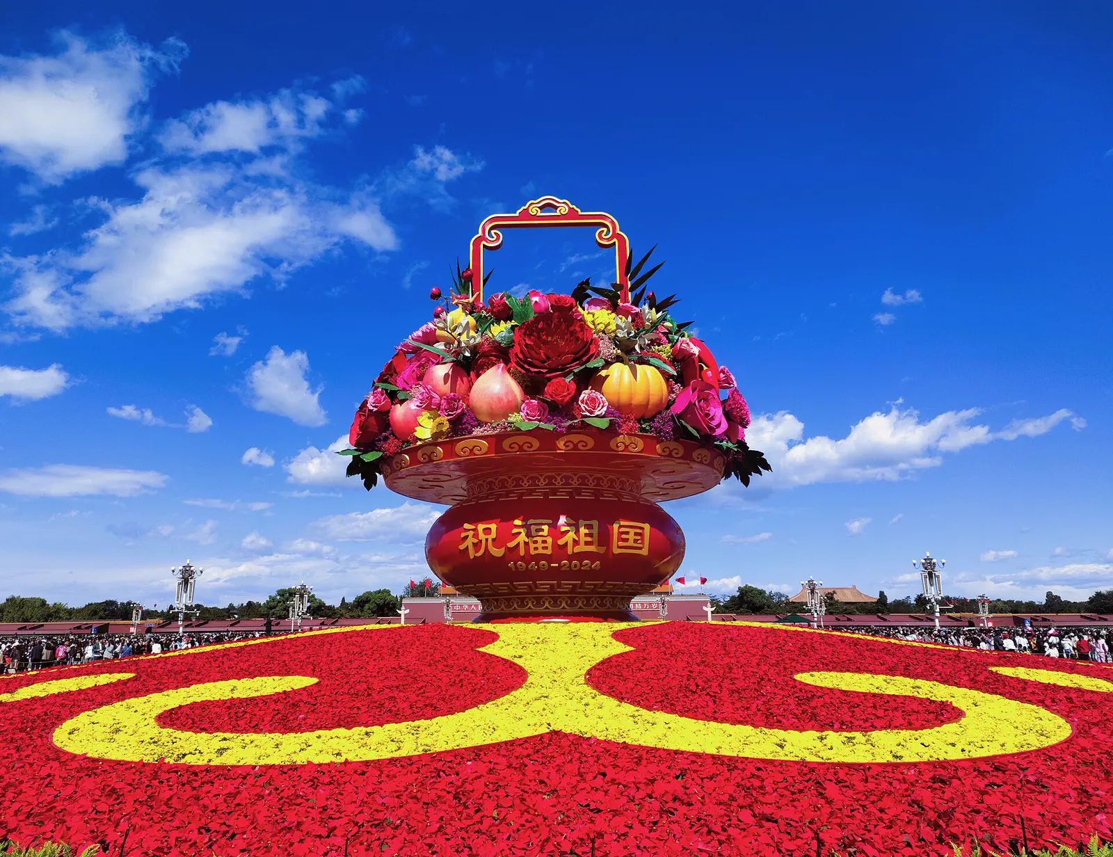 Tiananmen Square: large decorative flower basket sculpture on a red and yellow floral display under blue sky