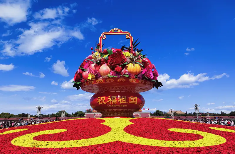 Tiananmen Square: large decorative flower basket sculpture on a red and yellow floral display under blue sky