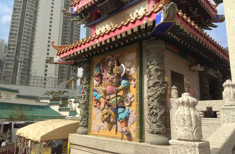 Wong Tai Sin Temple: the red-columned main hall with a carved stone screen and tower blocks behind
