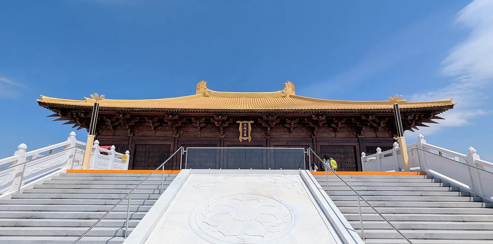 Mt Wutai: temple building with a gold tiled roof atop a wide white stone stairway under blue sky