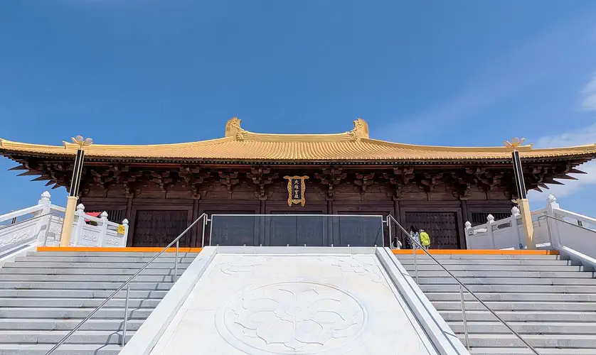 Mt Wutai: temple building with a gold tiled roof atop a wide white stone stairway under blue sky