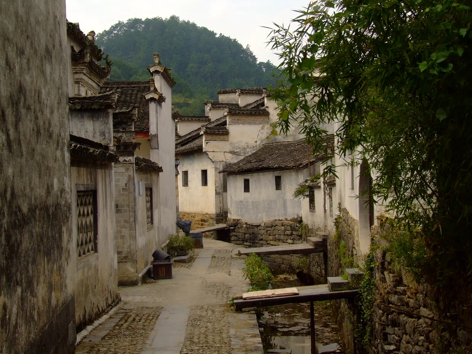Xidi Ancient Village: white-walled traditional houses with grey tiled roofs along a narrow stone alley