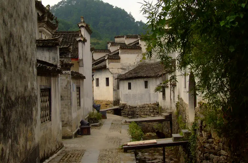 Xidi Ancient Village: white-walled traditional houses with grey tiled roofs along a narrow stone alley