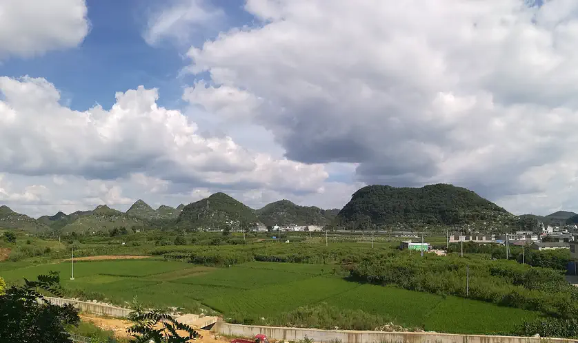 Anshun: green fields and rolling hills under a partly cloudy sky