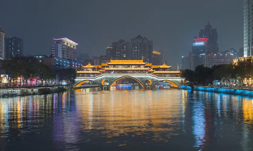 Chengdu: Anshun Bridge lit in gold at night, reflected in the Jin River below city towers