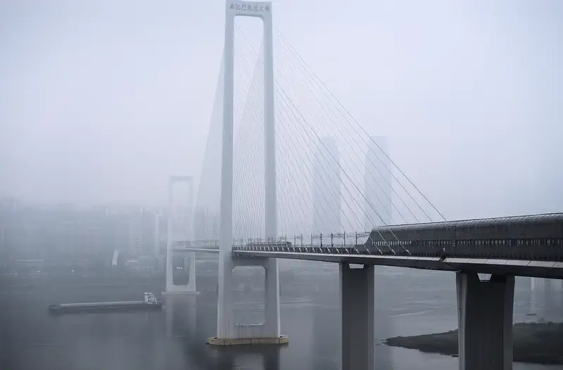 Chongqing: the cable-stayed Nanjimen rail bridge over the Yangtze, its towers fading into river fog