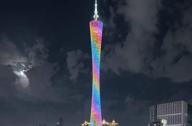 Guangzhou: Canton Tower lit in rainbow colours at night beside the Pearl River