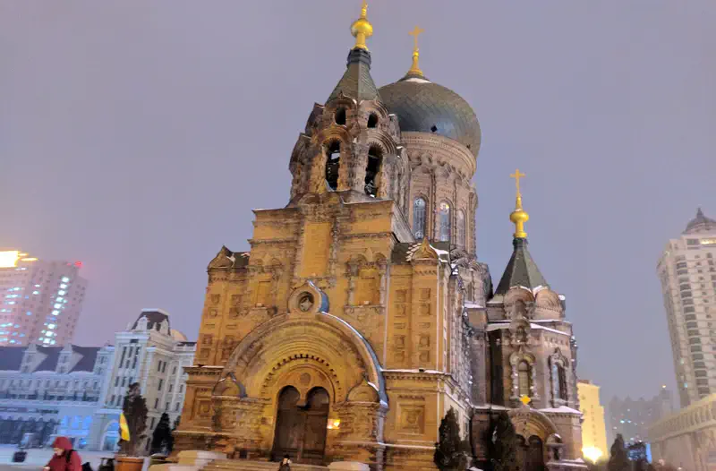 Harbin: the green domes and brick walls of Saint Sophia Cathedral at dusk in winter