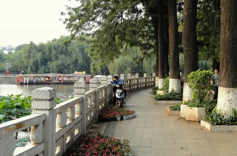 Kunming: lakeside promenade with a railing, trees, and boats on the water