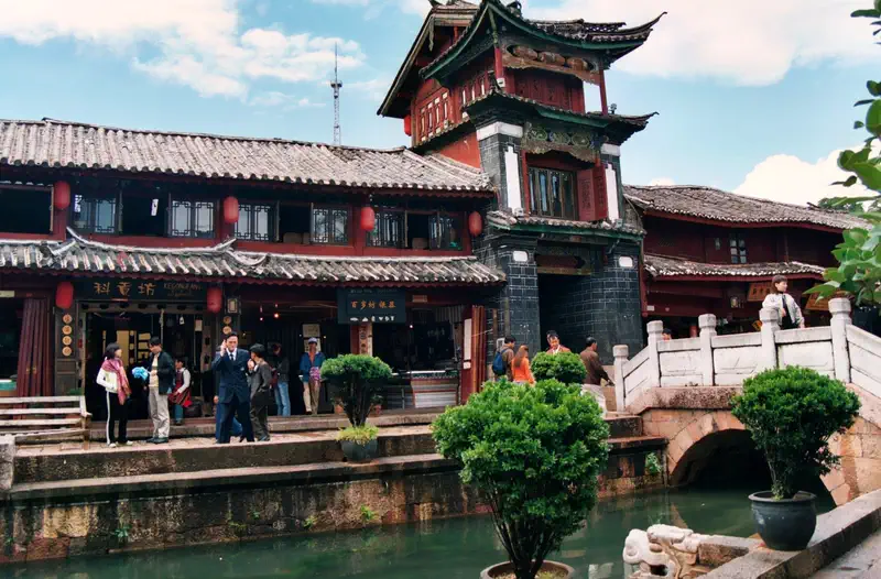 Lijiang: canal lined with traditional buildings, an arched bridge, and pedestrians