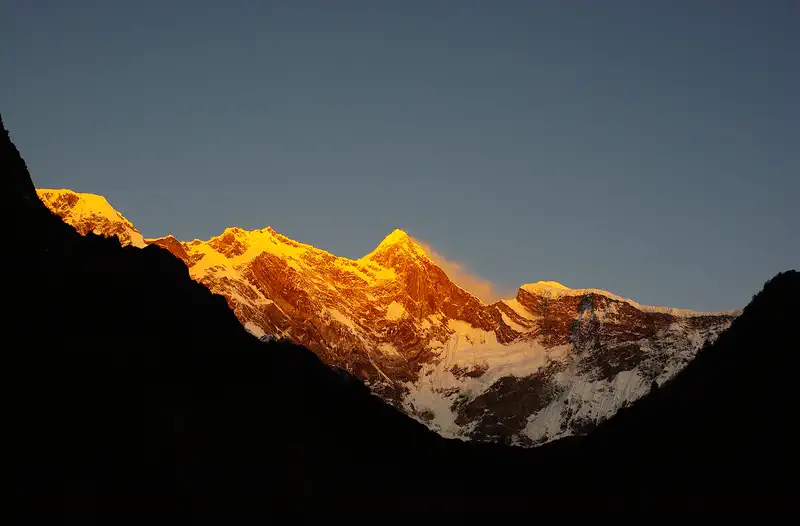 Nyingchi: the snow ridge of Namcha Barwa lit gold above dark foothills
