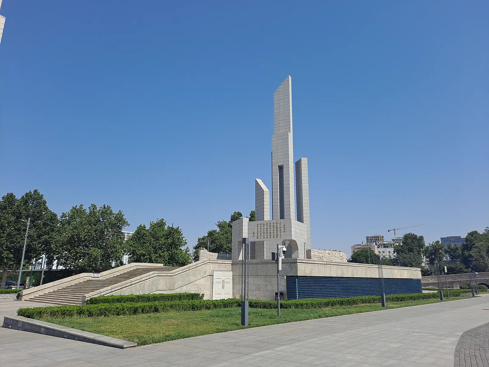 Shijiazhuang: tall white monument spire in a landscaped plaza with trees