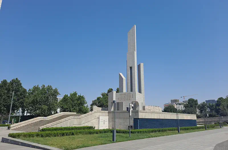 Shijiazhuang: tall white monument spire in a landscaped plaza with trees