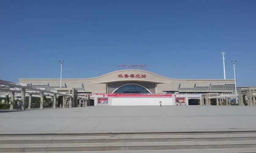 Turpan: modern building with a wide plaza and flagpoles under blue sky