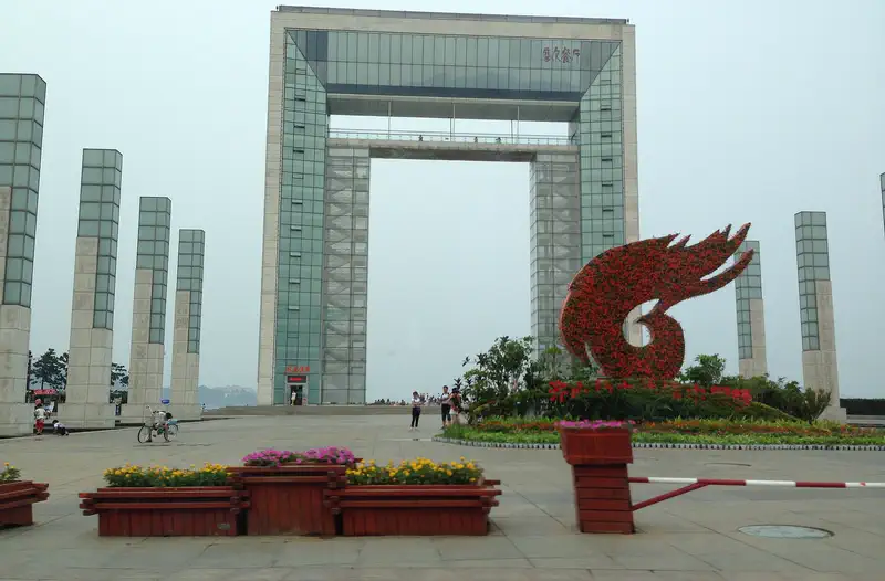 Weihai: a tall gate-shaped monument and red sculpture on a seafront plaza in Huancui district