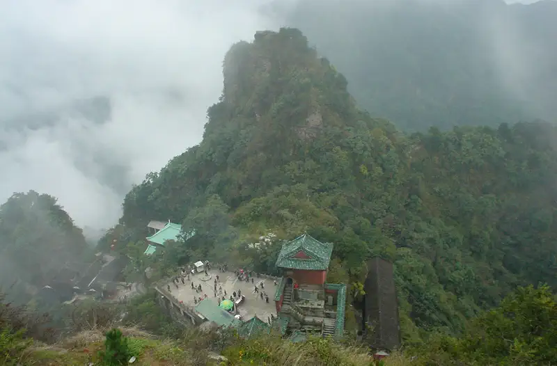 Wudang Mountains: misty green peaks with small temple buildings visible below