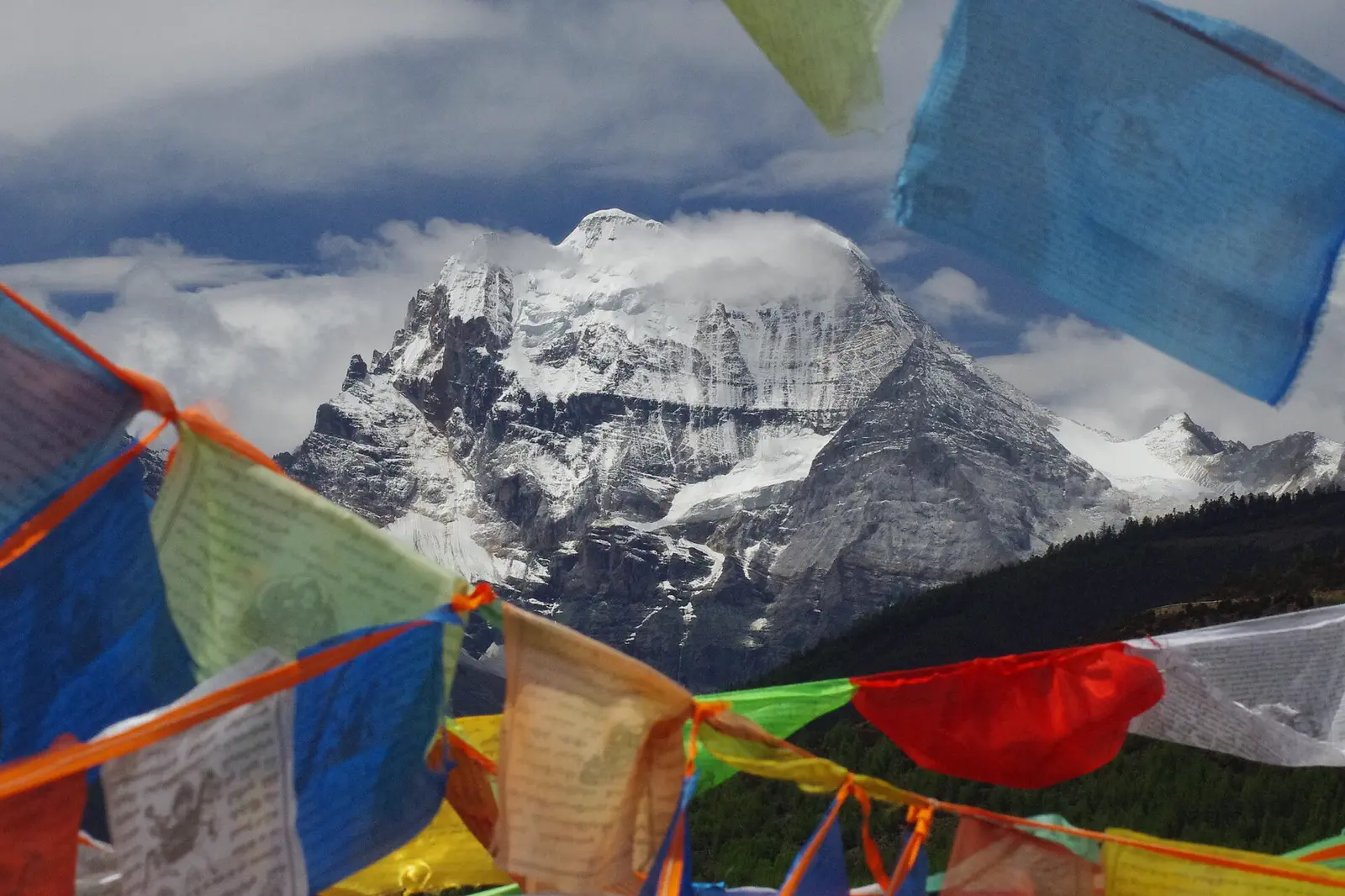 The snow peak of Xiannairi seen through prayer flags at Yading, Sichuan