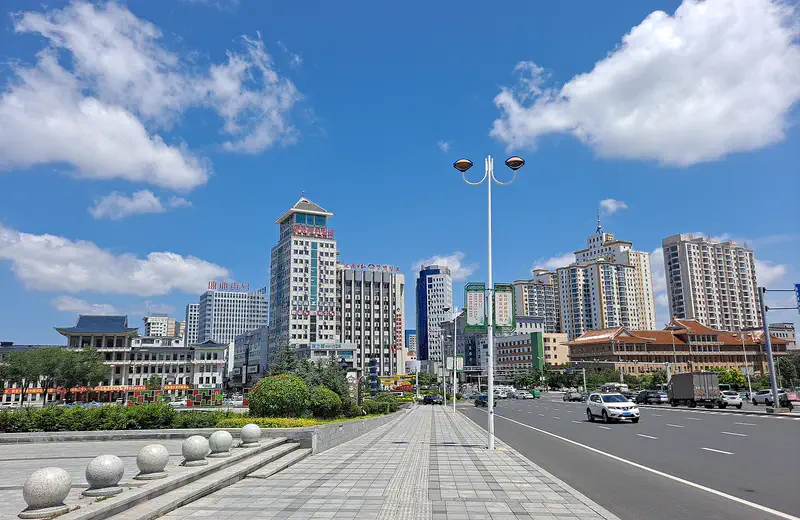Yanji: a wide city street lined with mid-rise buildings under a blue sky