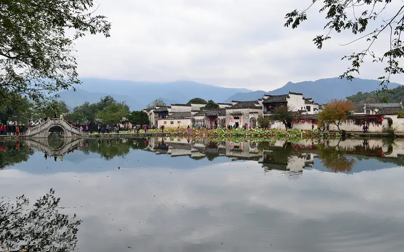 Yixian: whitewashed Huizhou houses and an arched bridge reflected in Hongcun's South Lake