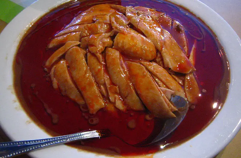 Bang Bang Chicken: shredded chicken pieces in a dark red chili oil sauce, served in a white bowl
