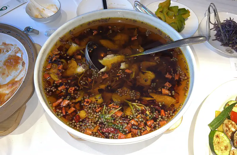 Boiled Fish in Chilli Oil: fish slices in a bowl of red chilli oil scattered with dried chillies and peppercorns