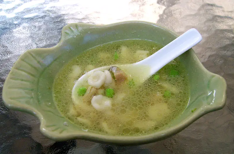 Cat's Ear Noodles: small pinched pasta pieces in a clear soup with greens, served in a green bowl