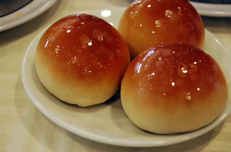 Char Siu Bao (BBQ Pork Buns): three glossy brown baked buns arranged on a white plate