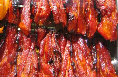 Char Siu (BBQ Pork): rows of glossy red-glazed roasted meat pieces hanging on display