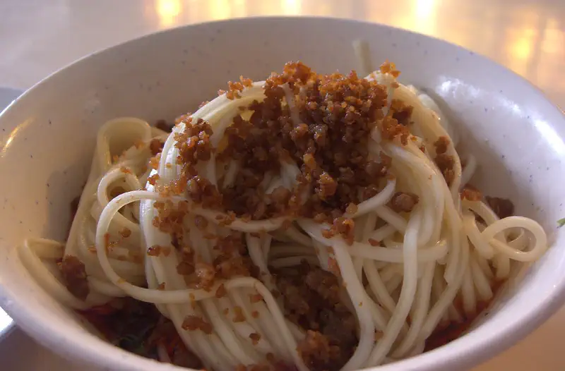 Dan Dan Noodles: white noodles topped with browned minced meat in a bowl